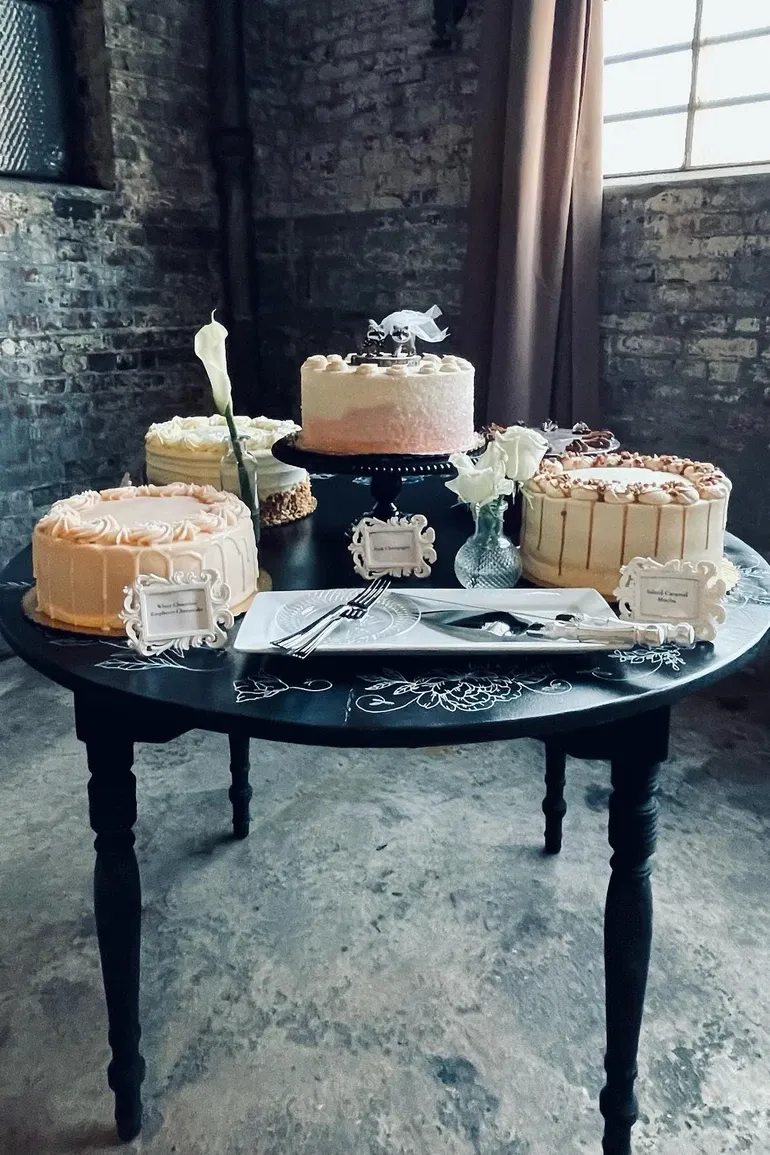 Dessert table with four frosted cakes on a black table