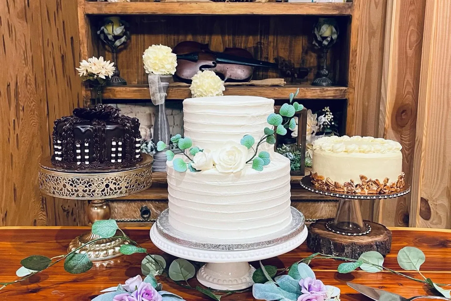 Two buttercream cakes on a wood table with a violin behind