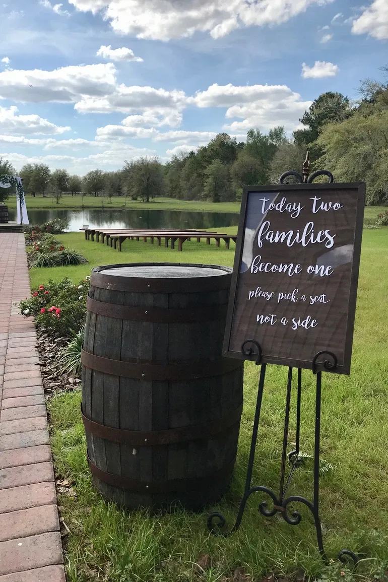 Whiskey barrel with a pick a seat not a side sign overlooking the lawn