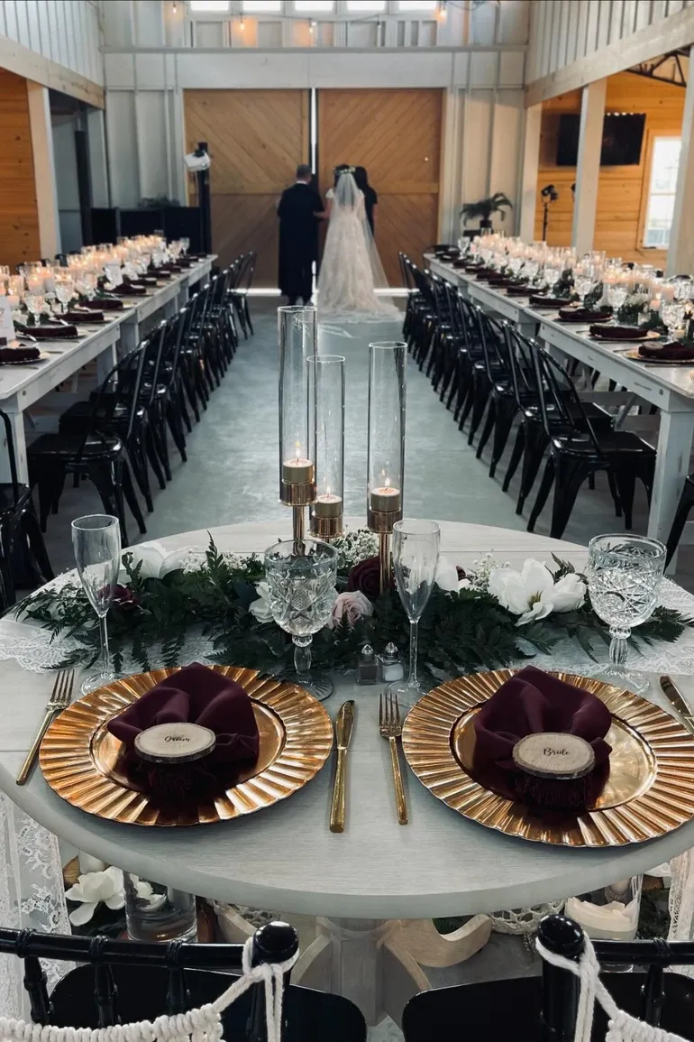 A bride walking the aisle between long candlelit tables.