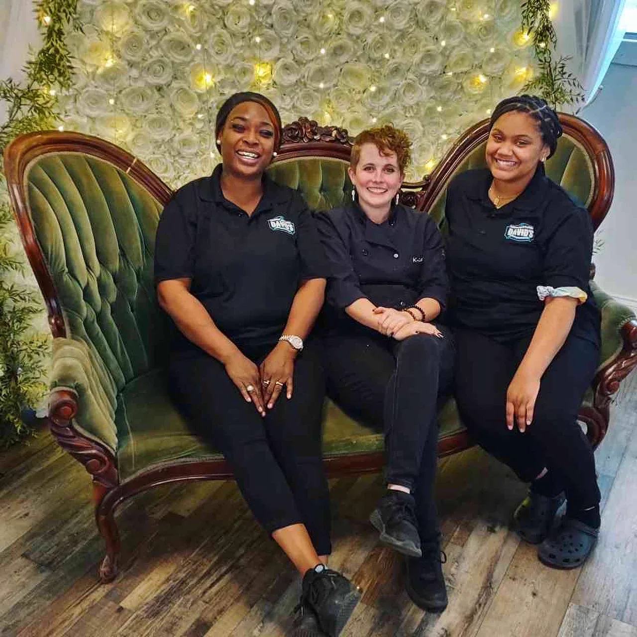 Three catering staff seated together on a green velvet couch