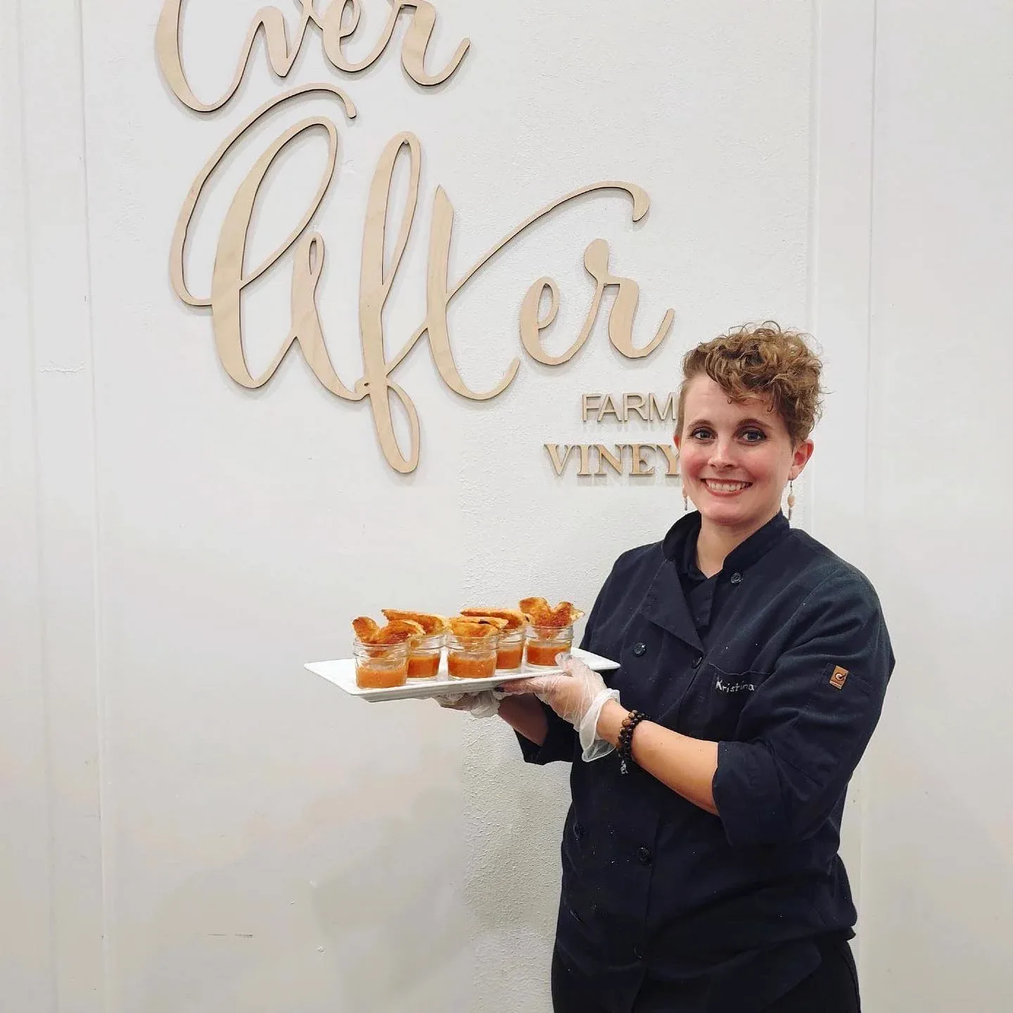 A chef presenting a tray of appetizers beneath a venue sign