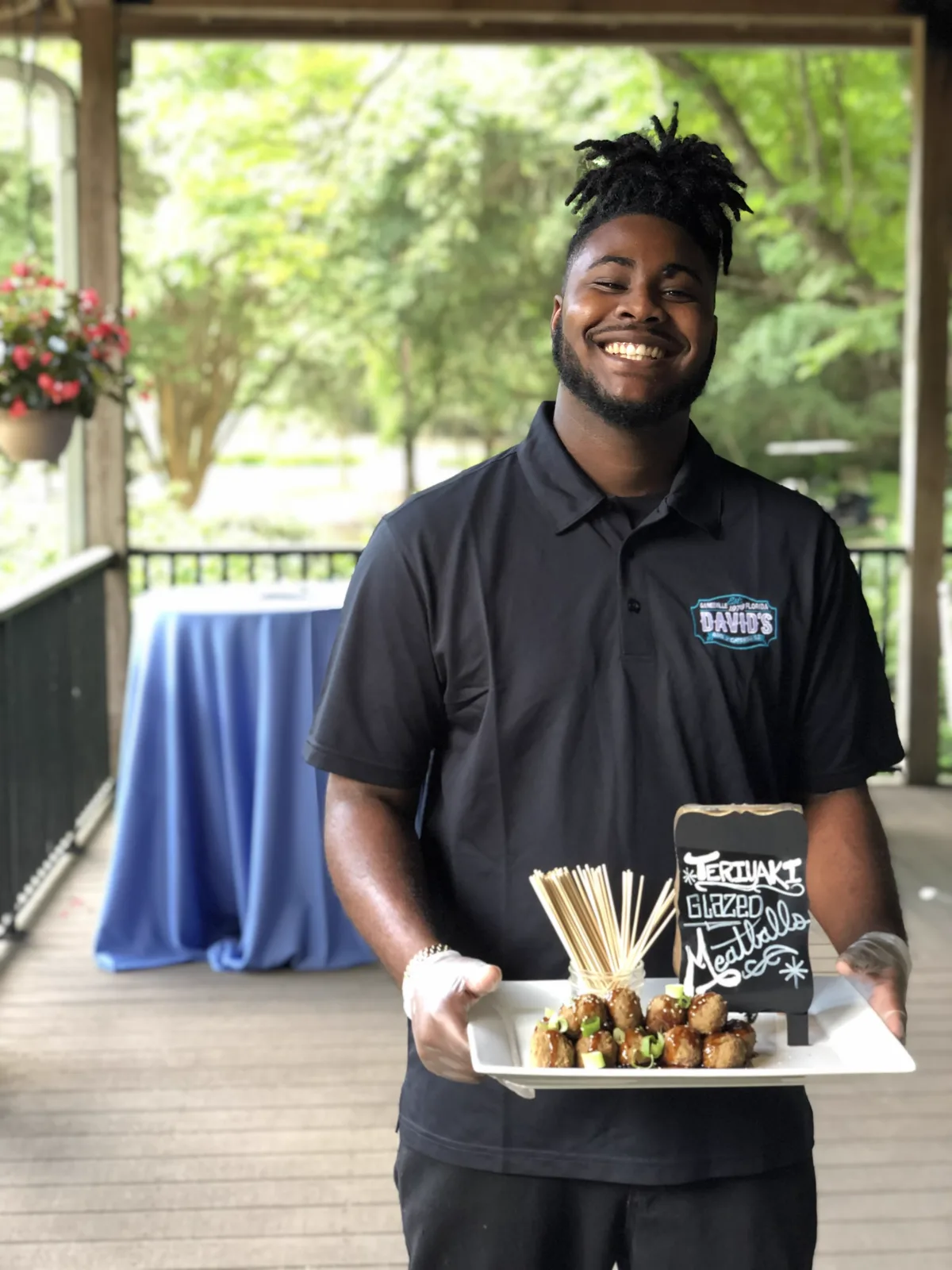A server carrying a tray of skewered appetizers on a porch