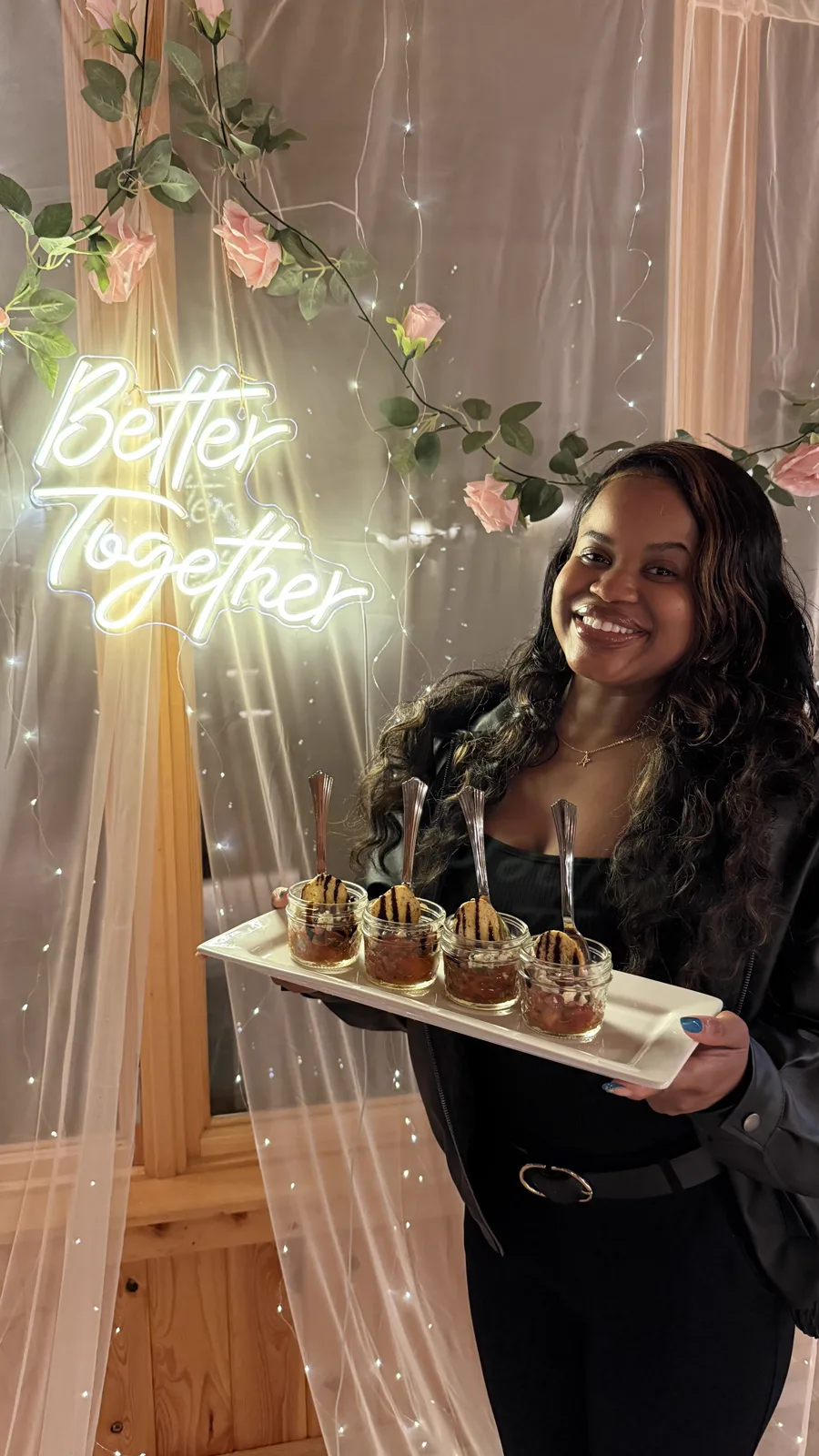 A server holding a tray beneath a Better Together neon sign