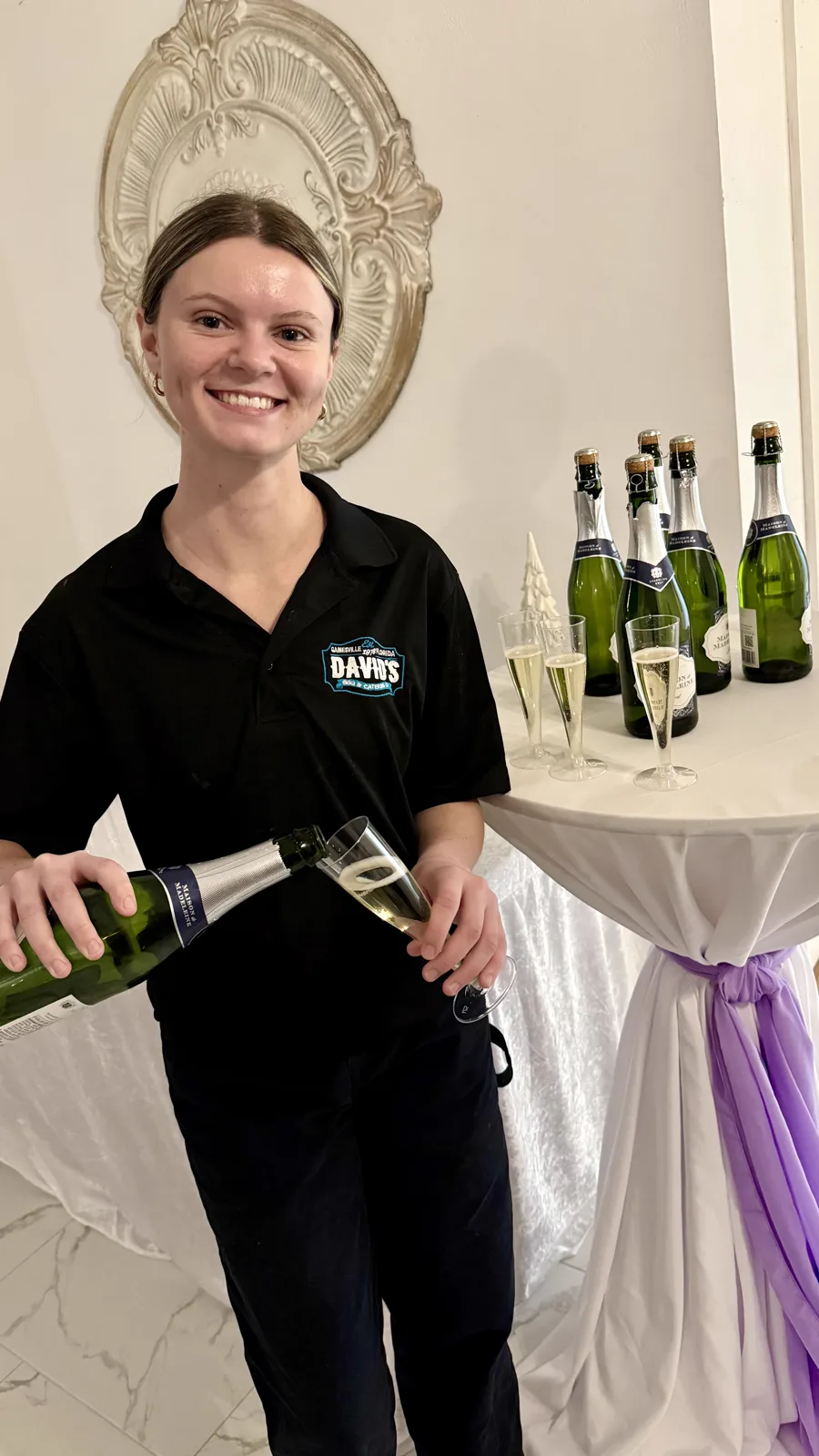A server pouring champagne beside a tray of filled glasses