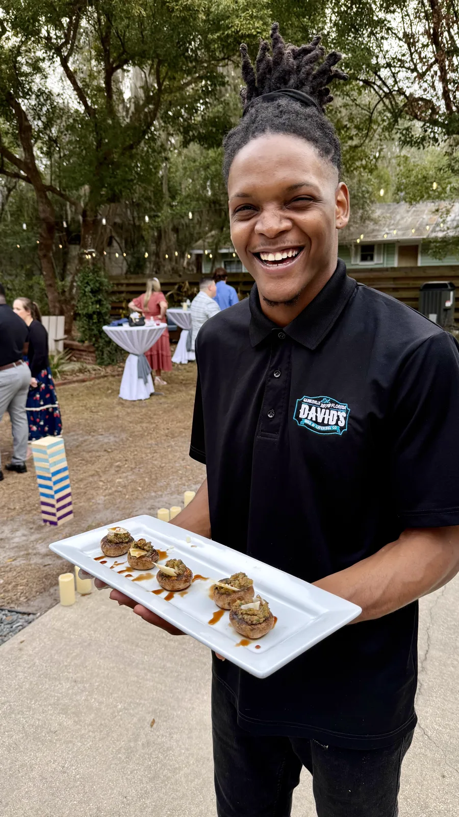 A smiling server carrying appetizers across the lawn