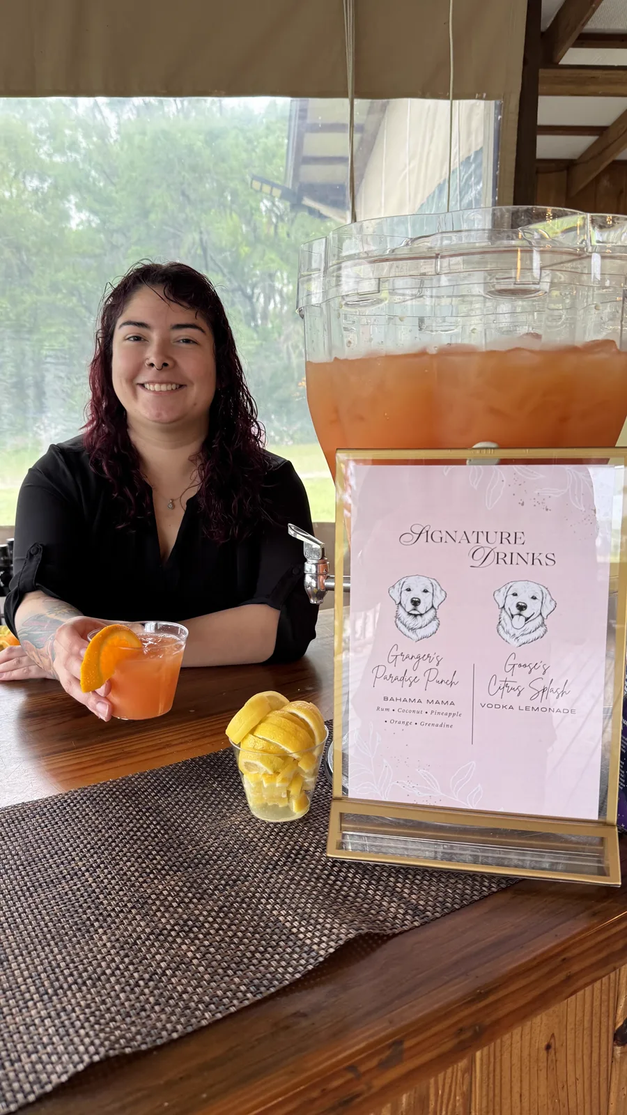 A server behind a signature drinks station with citrus and menus