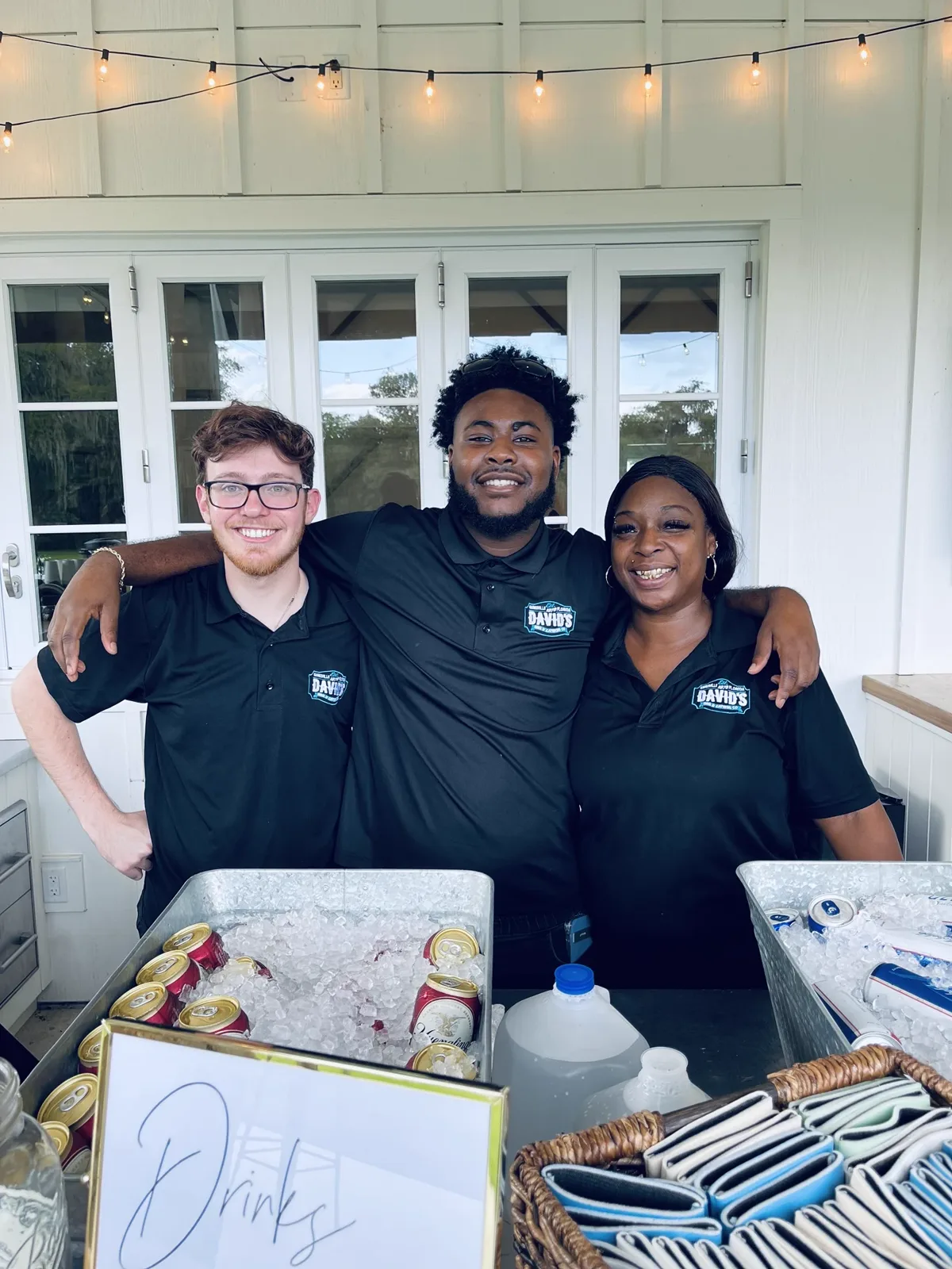 Three catering staff behind a drinks station