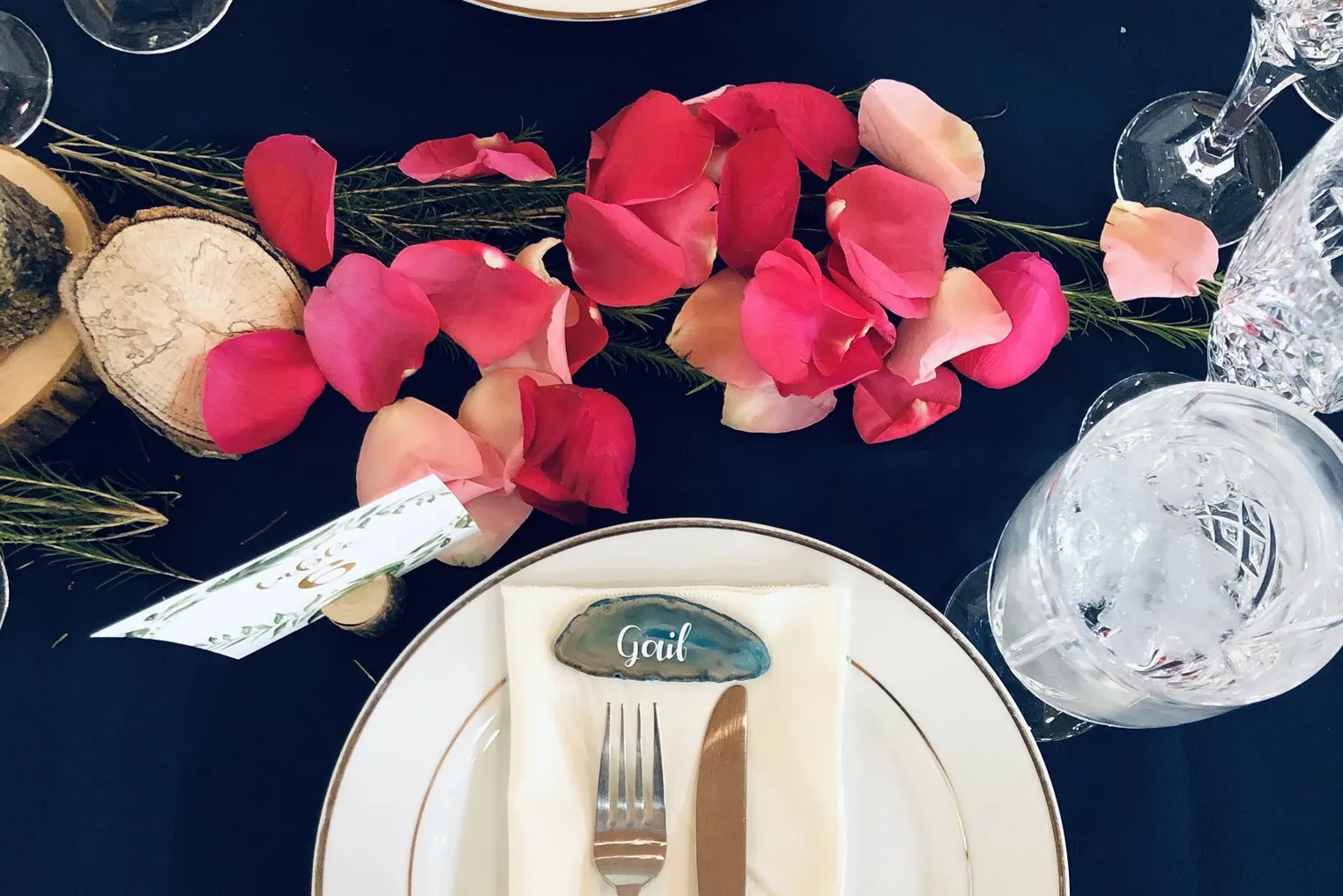 Rose petals and an agate place card reading Gail