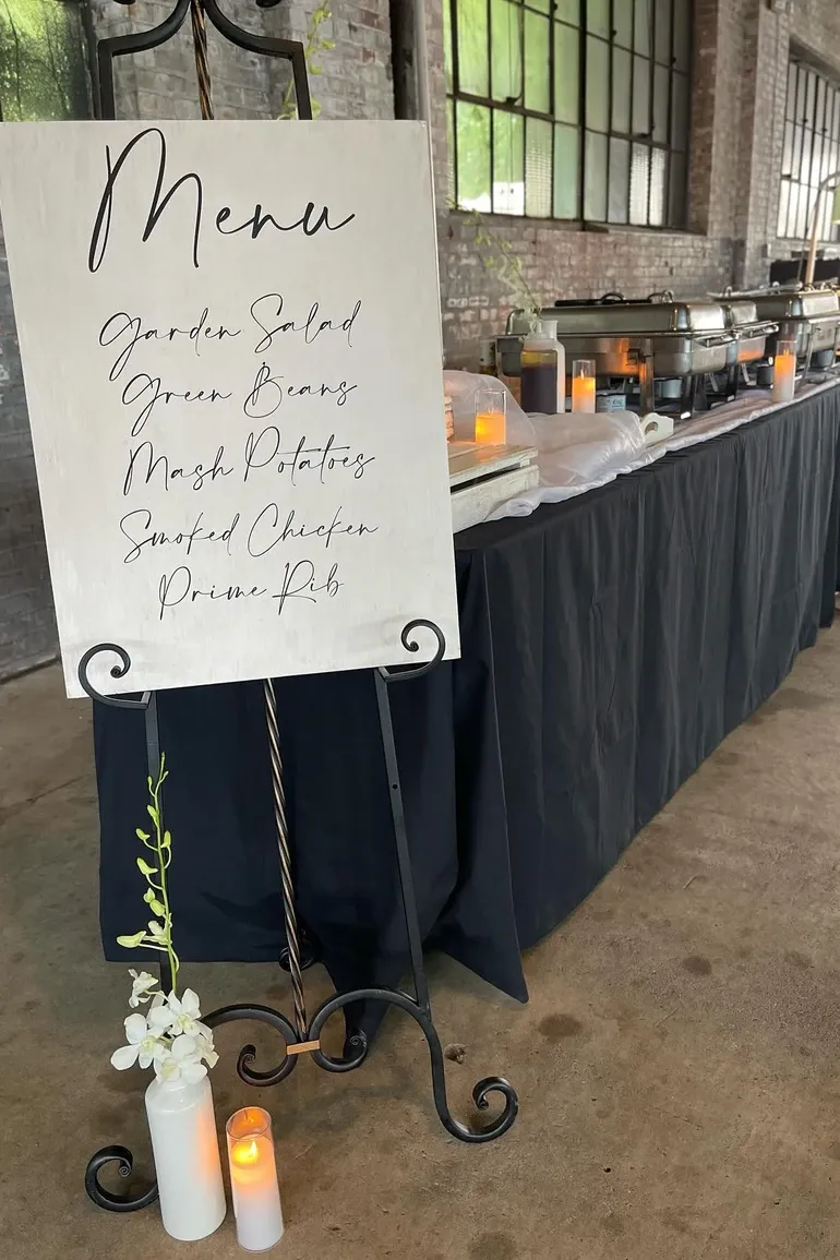 Hand scripted menu board listing salad, green beans, mashed potatoes, smoked chicken, and prime rib