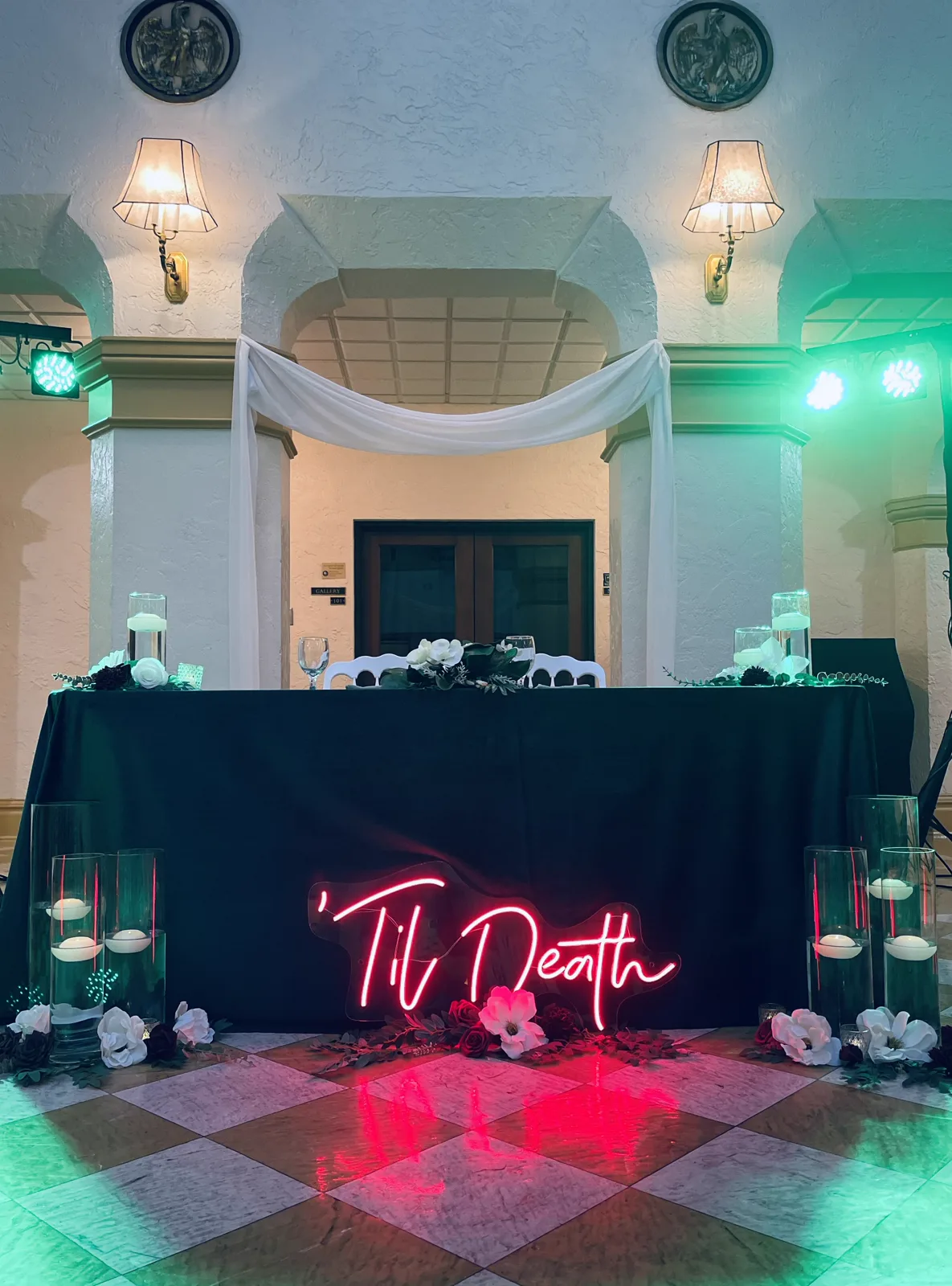 A Til Death neon sign glowing above a checkered dance floor