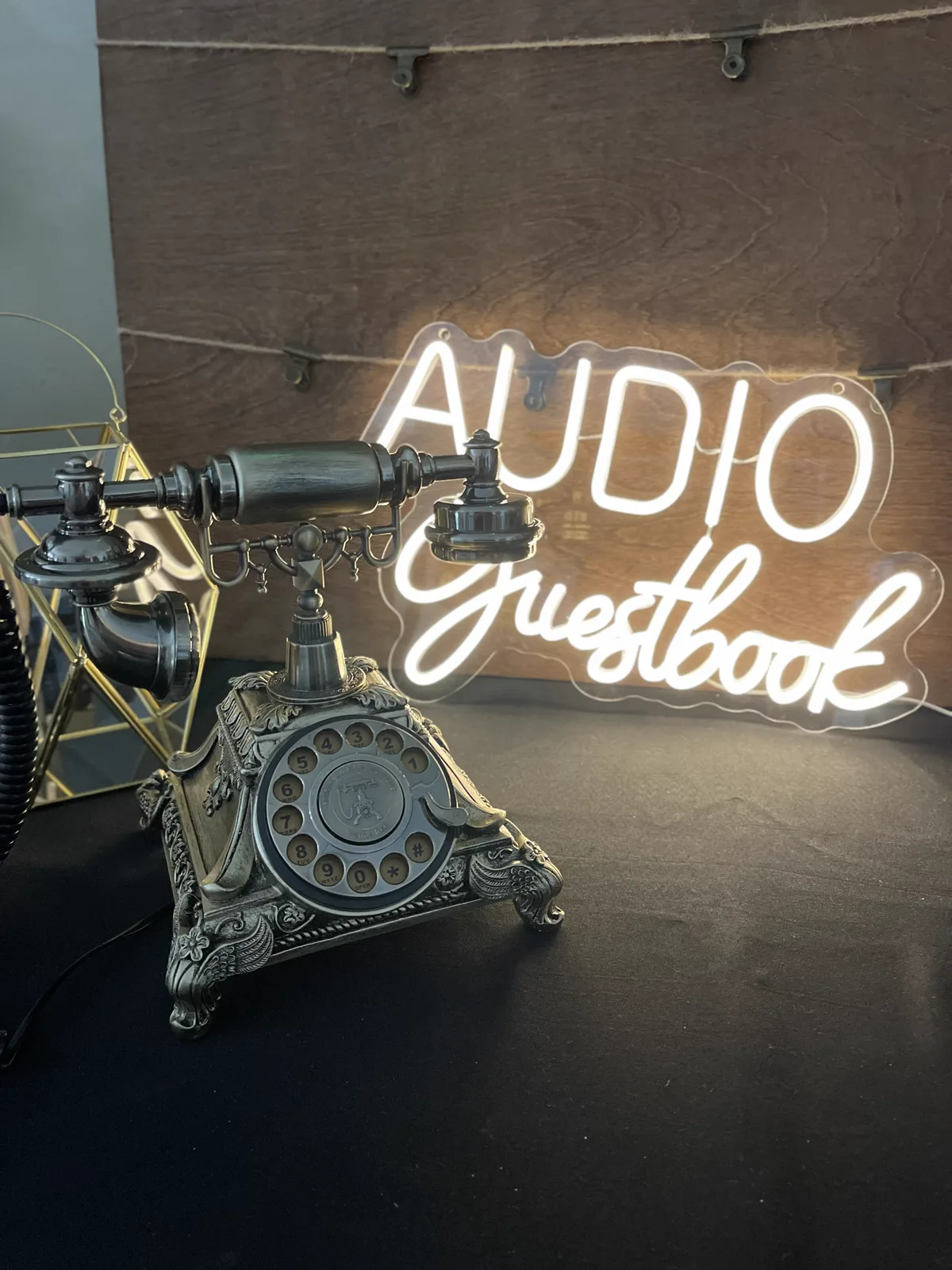 An Audio Guestbook neon sign beside a vintage rotary telephone