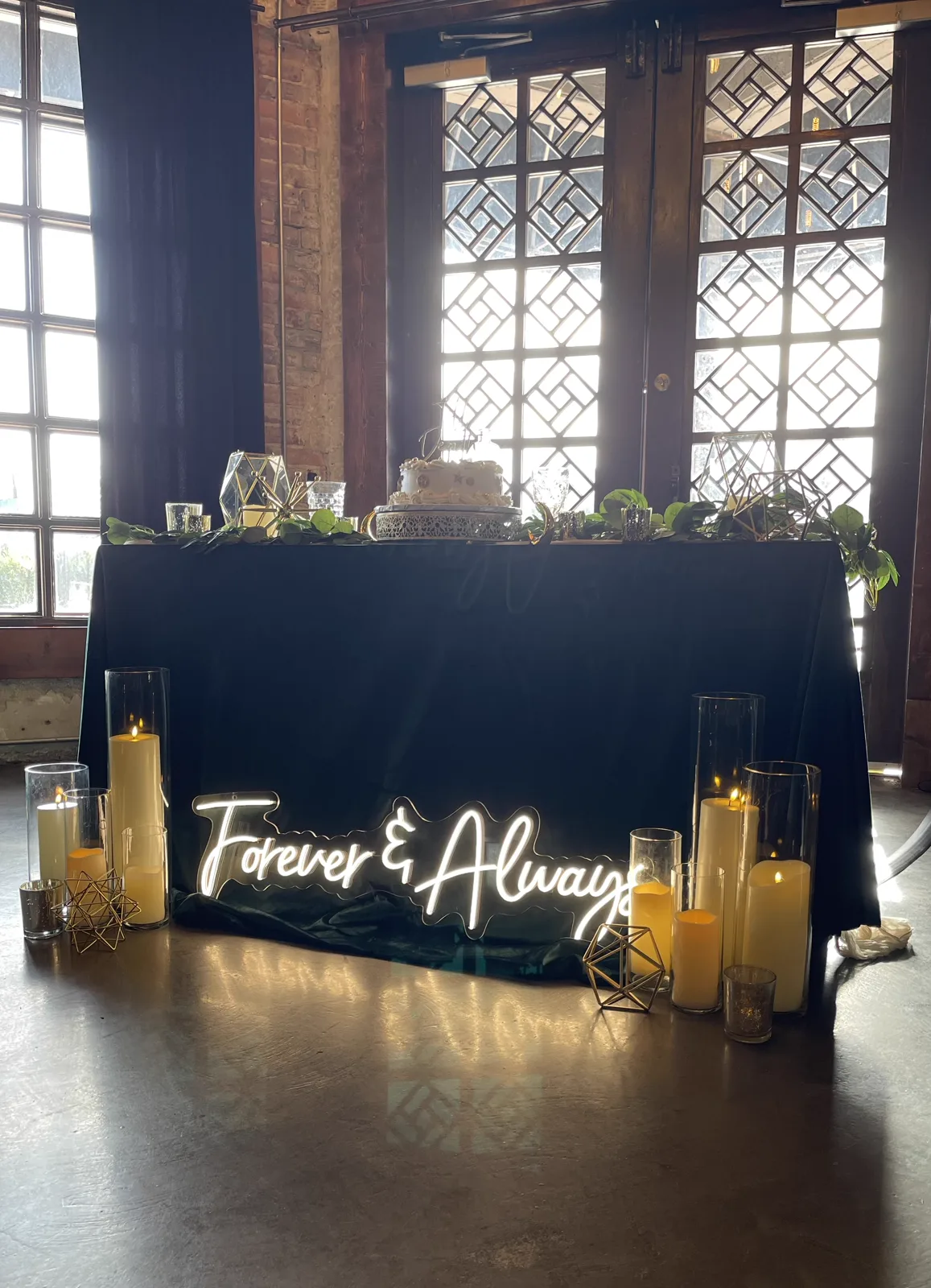 A Forever and Always neon sign glowing behind a row of candles