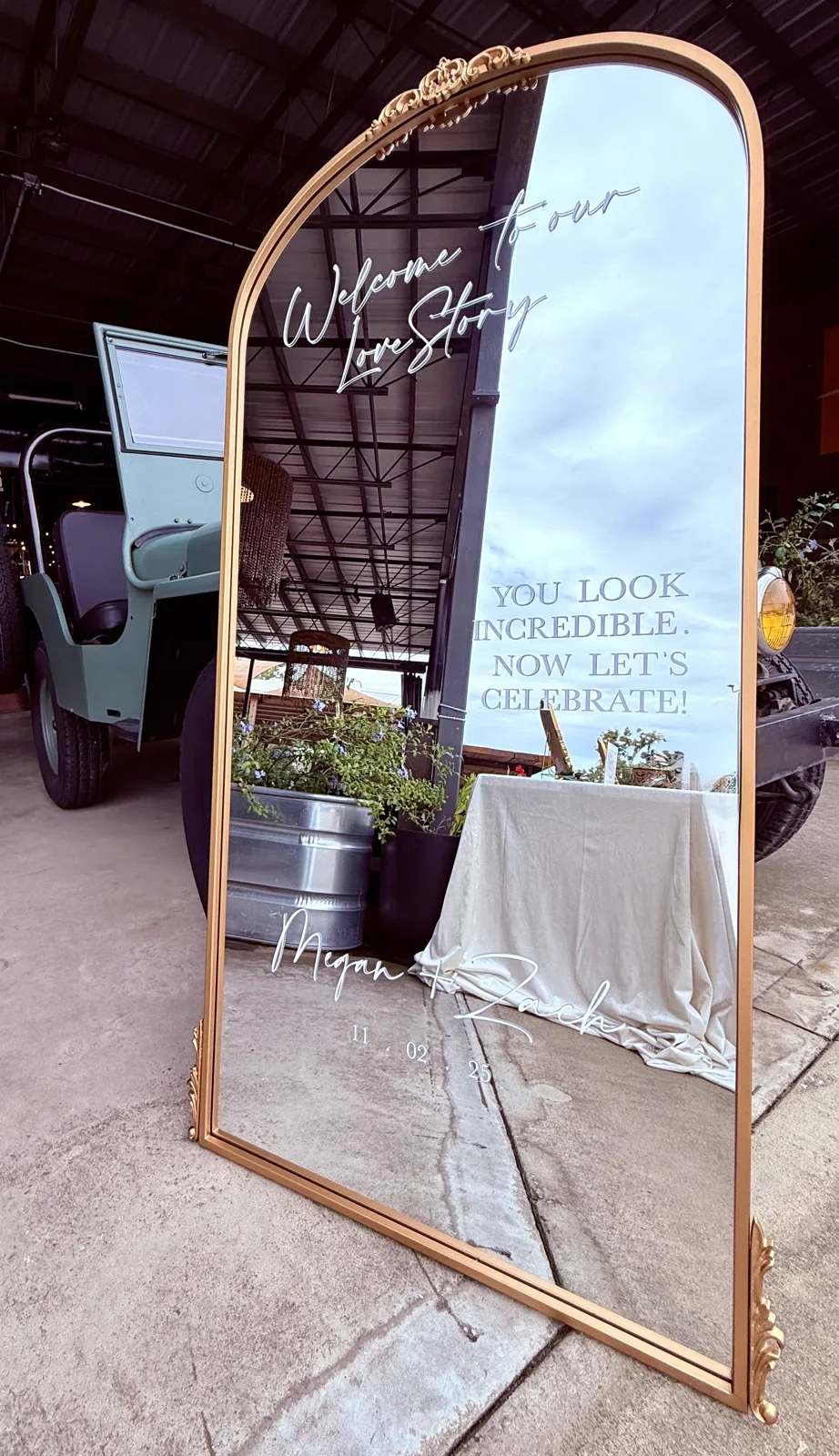 An arched mirror welcome sign draped in white fabric