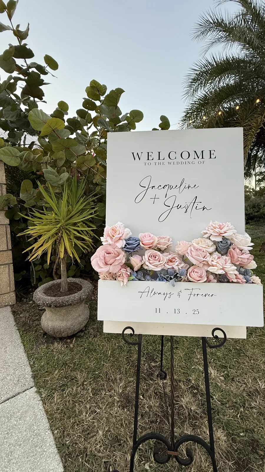 A wedding welcome sign on an easel framed by pink florals