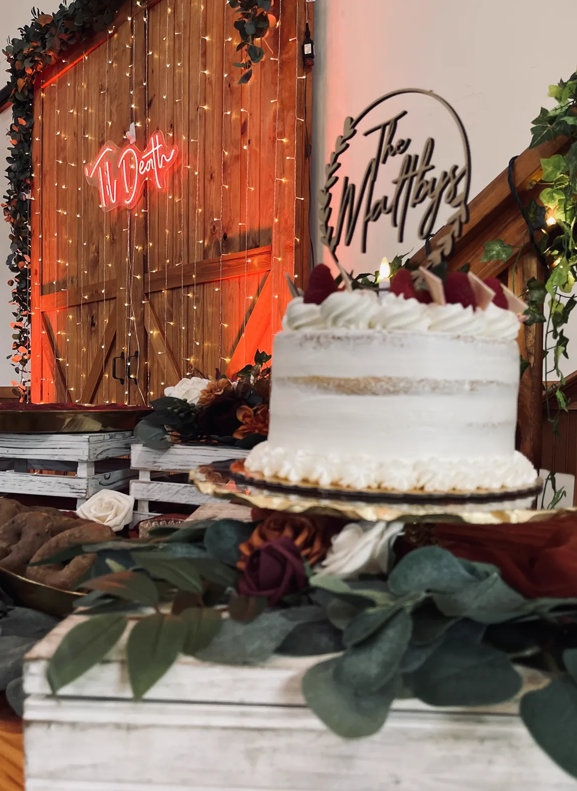 A white wedding cake in front of a warm neon backdrop