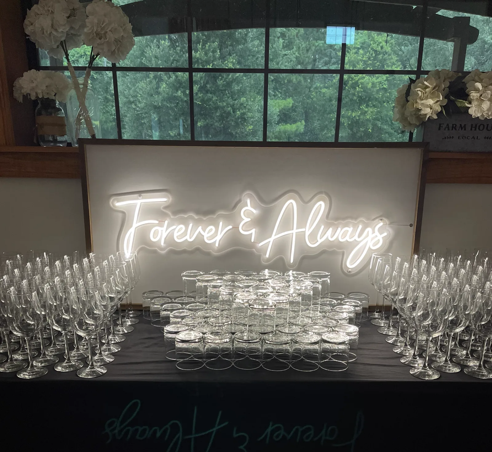 A Forever and Always neon sign above a wall of champagne glasses