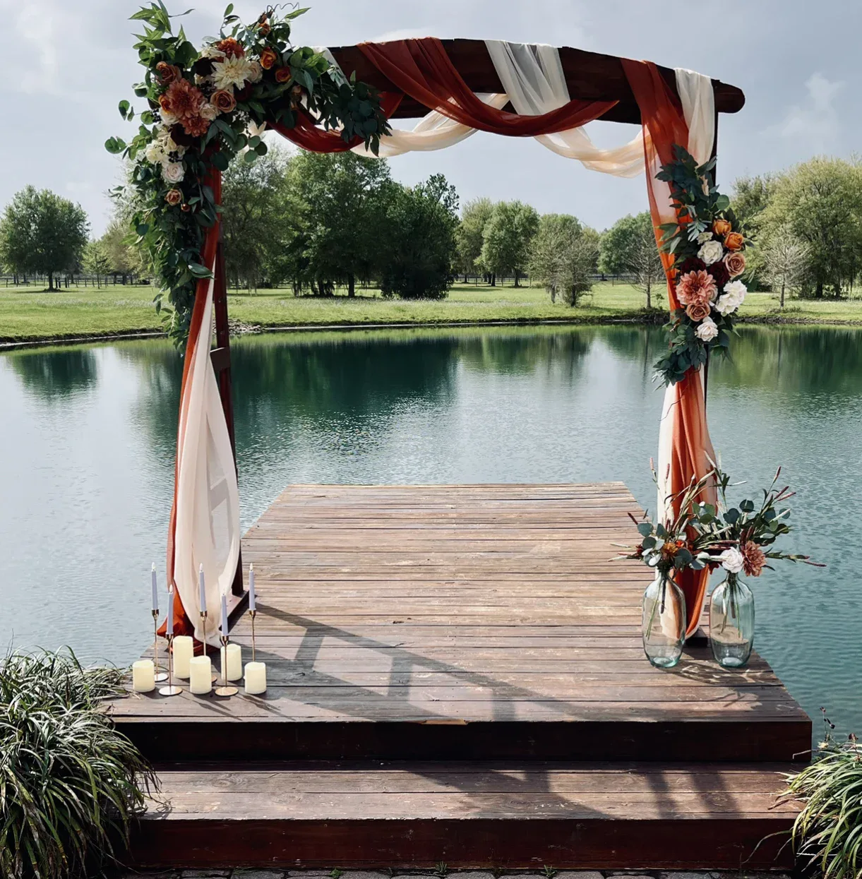 A floral arch on a wooden dock overlooking the water