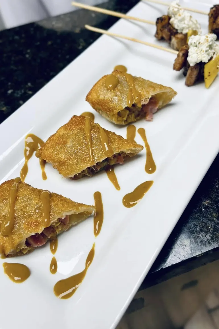 Fried pastry triangles drizzled with caramel on a white plate