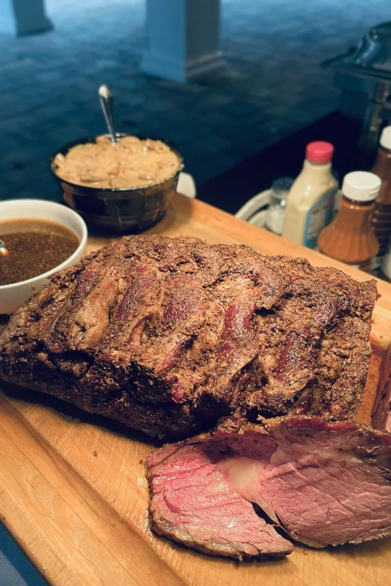 Prime rib carved on a wooden board with au jus