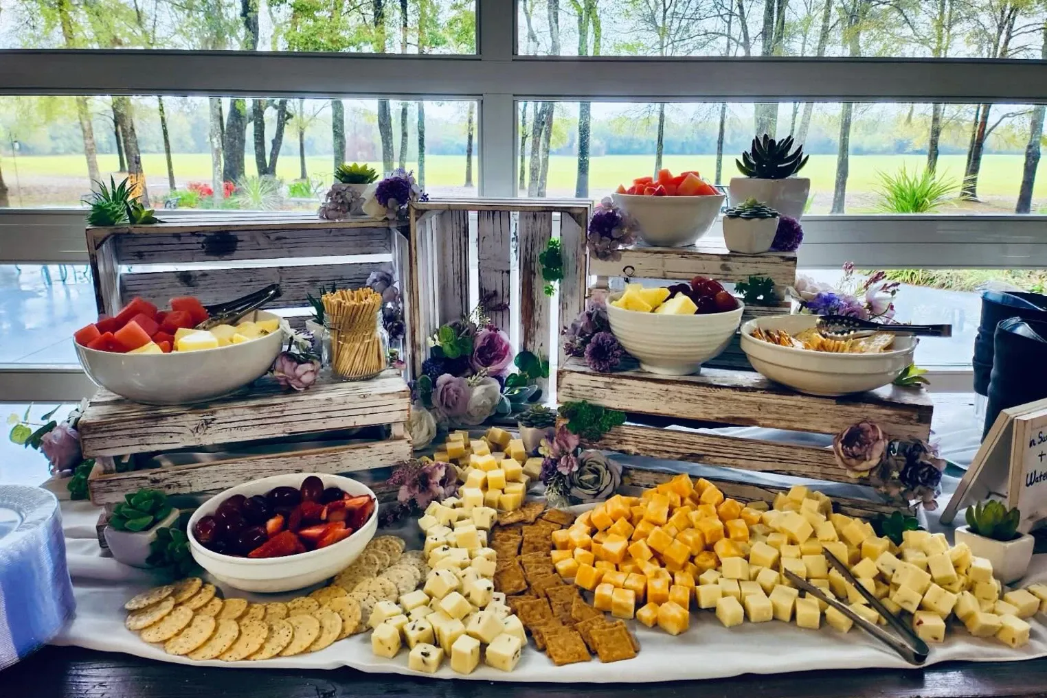 A grazing station built on wooden crates with fruit, cheese, and crackers.