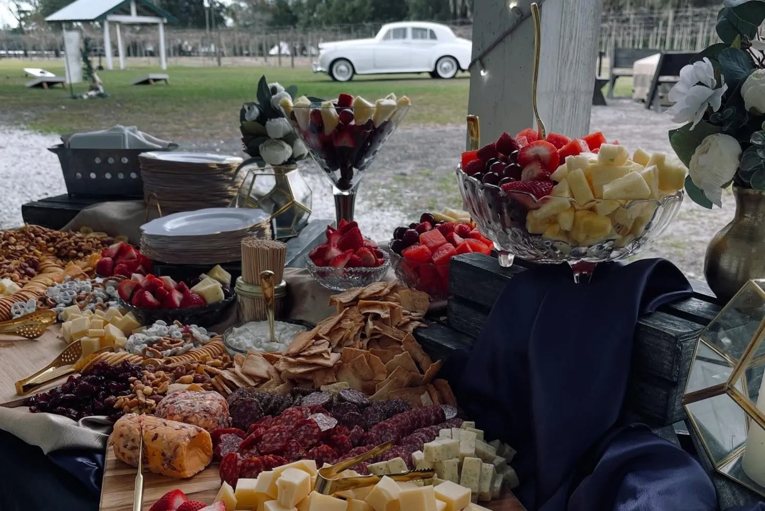 Grazing spread with fruit and cheese and a vintage car behind