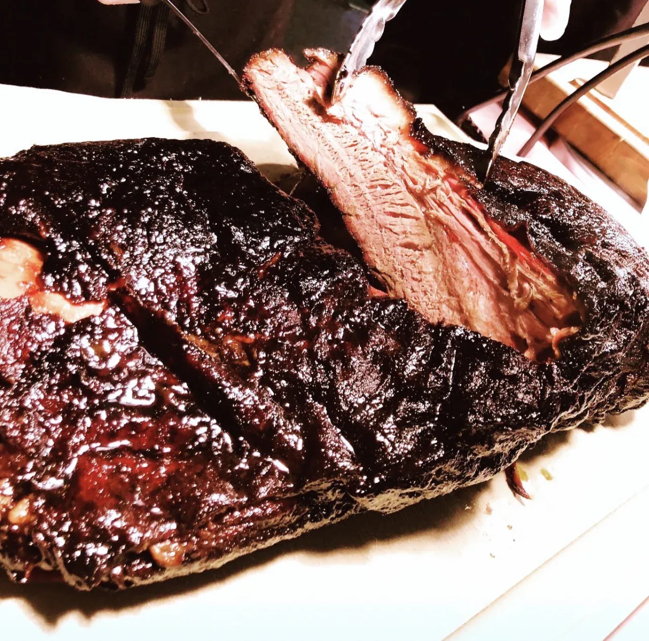 A rack of smoked ribs being lifted from the carving board