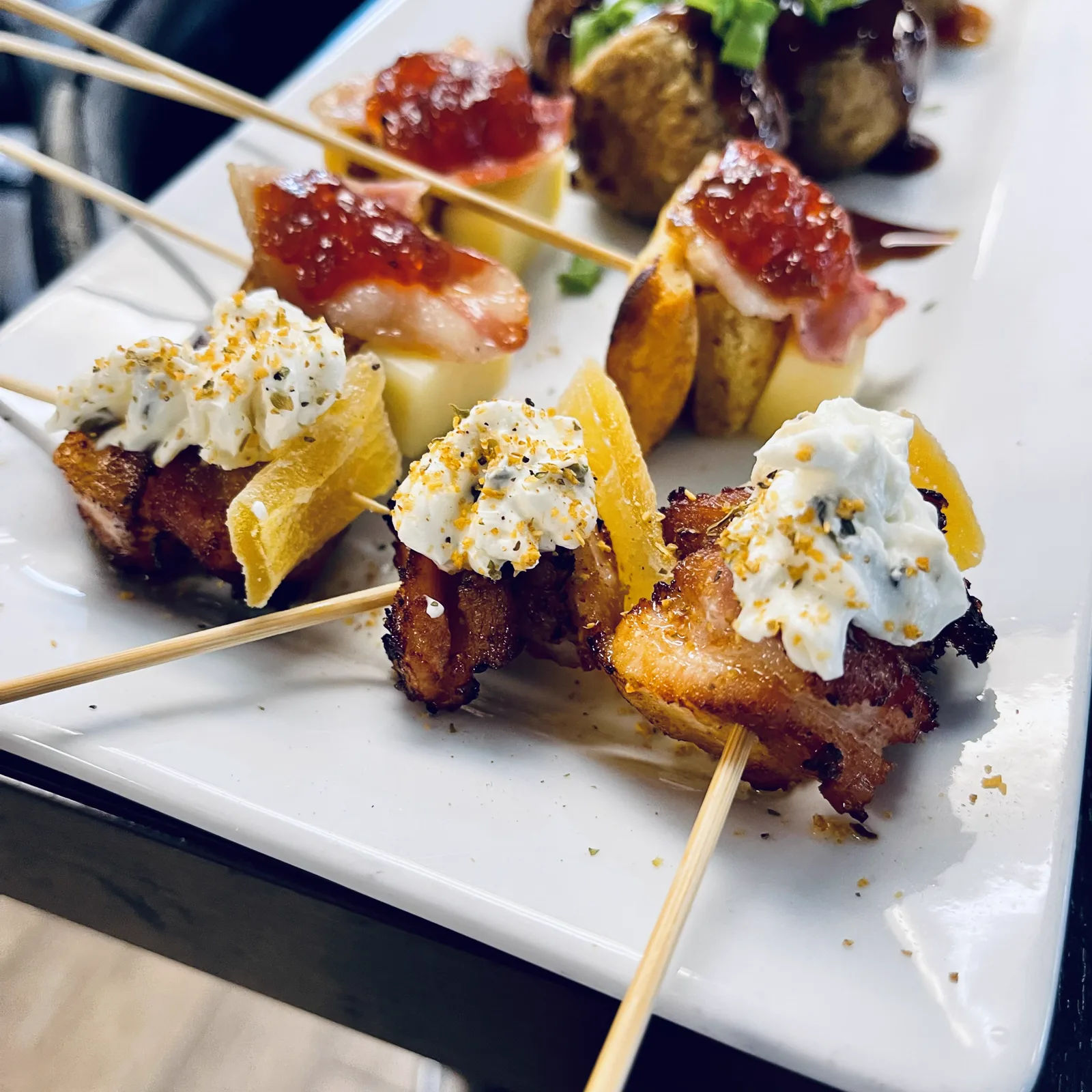 Skewered appetizers finished with pepper jelly on a white platter