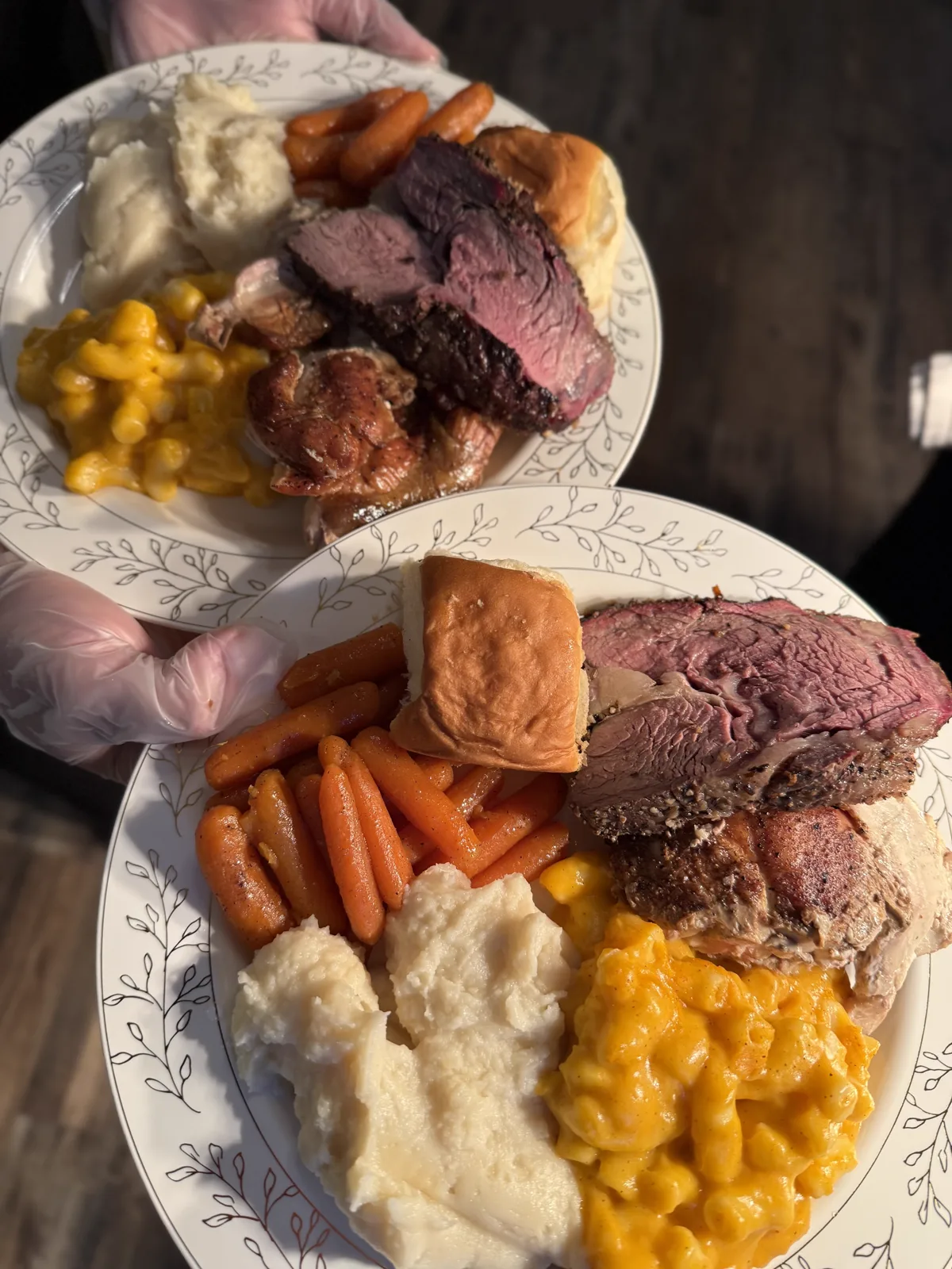 A dinner plate of prime rib, mac and cheese, carrots and a roll