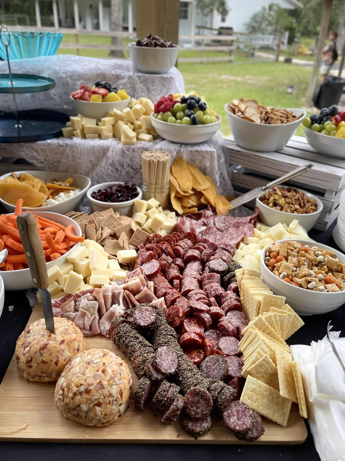 A charcuterie spread with fruit, nuts and cured meats set up outdoors