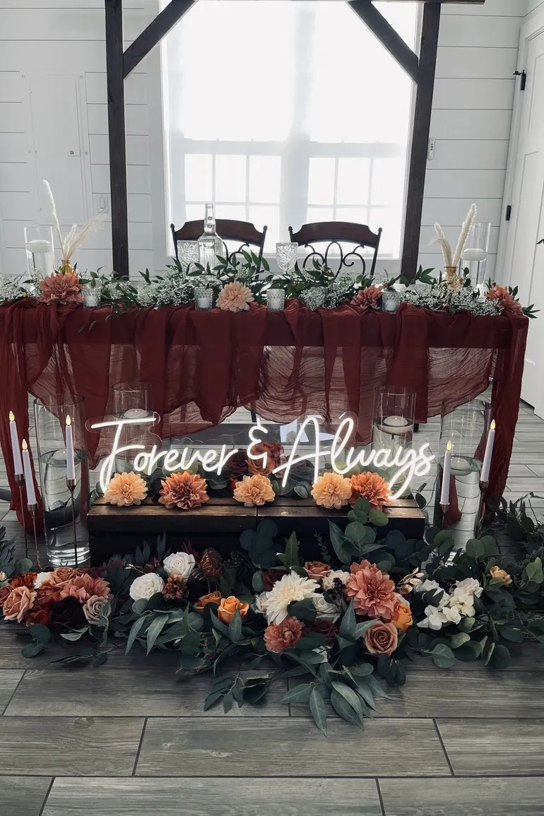 Sweetheart table with a burgundy runner and a Forever and Always neon sign