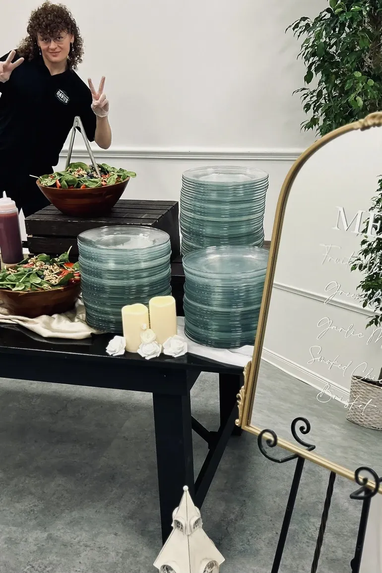 Server dressing salads beside a gold framed menu mirror