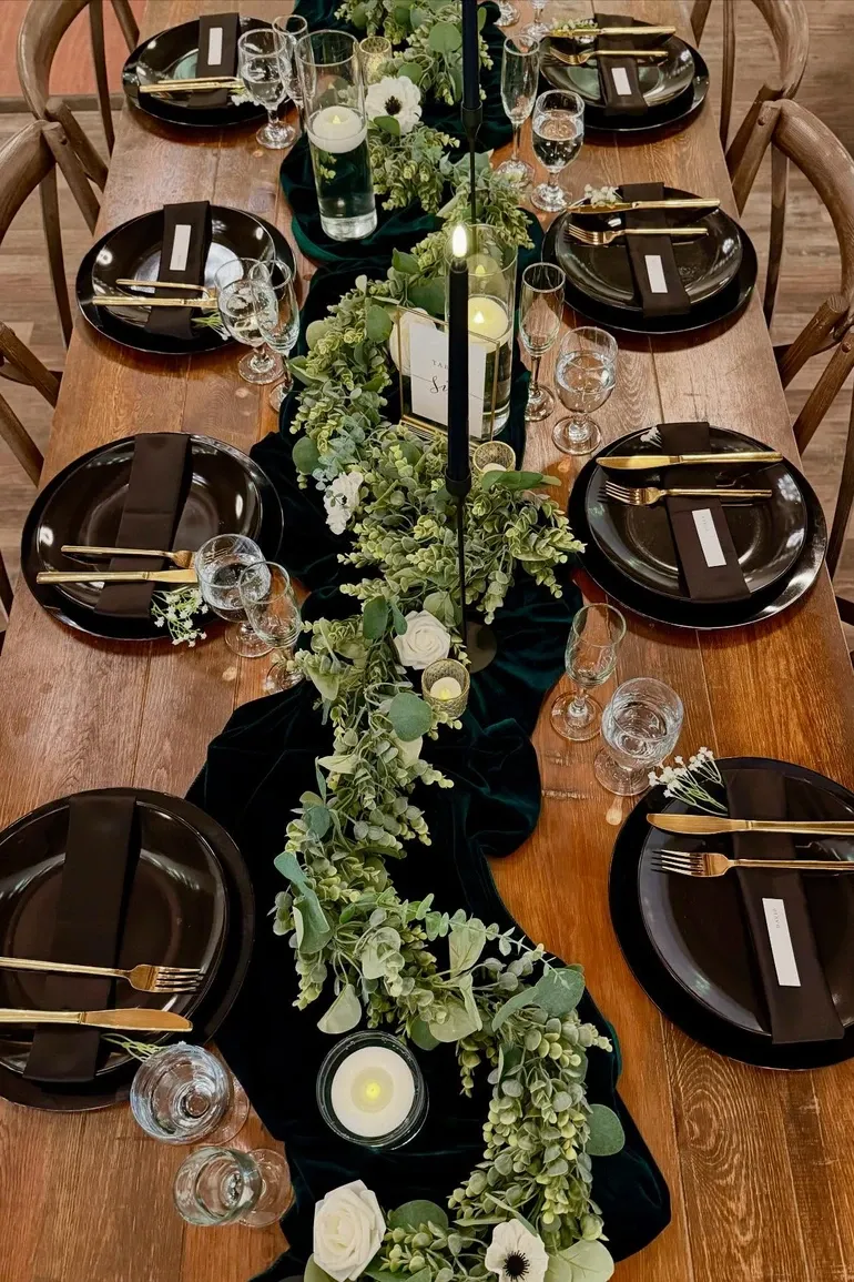 Black plates and gold flatware on a green velvet runner