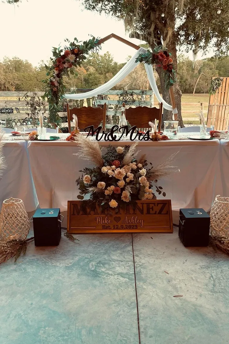 Outdoor Mr and Mrs head table beneath floral arches
