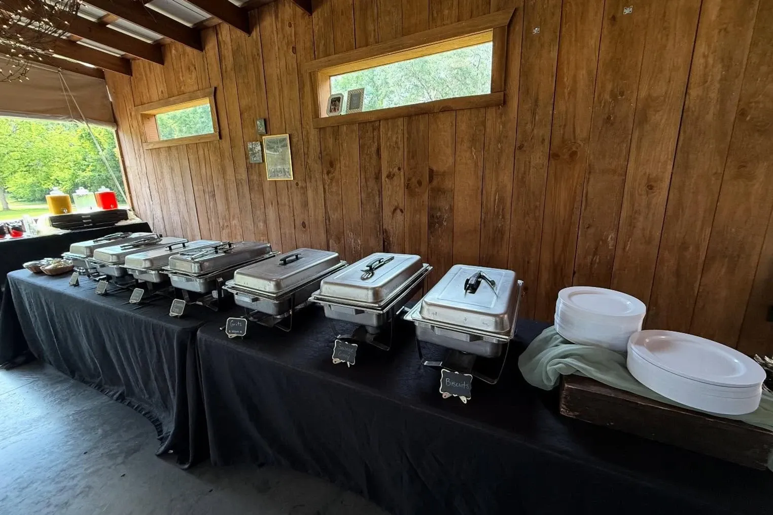 Buffet warmers lined on black linen in an open pavilion