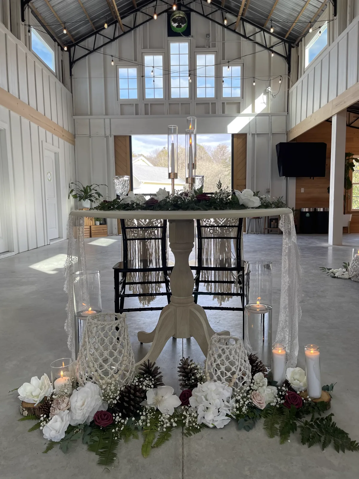 A barn reception hall draped in white with a sweetheart table