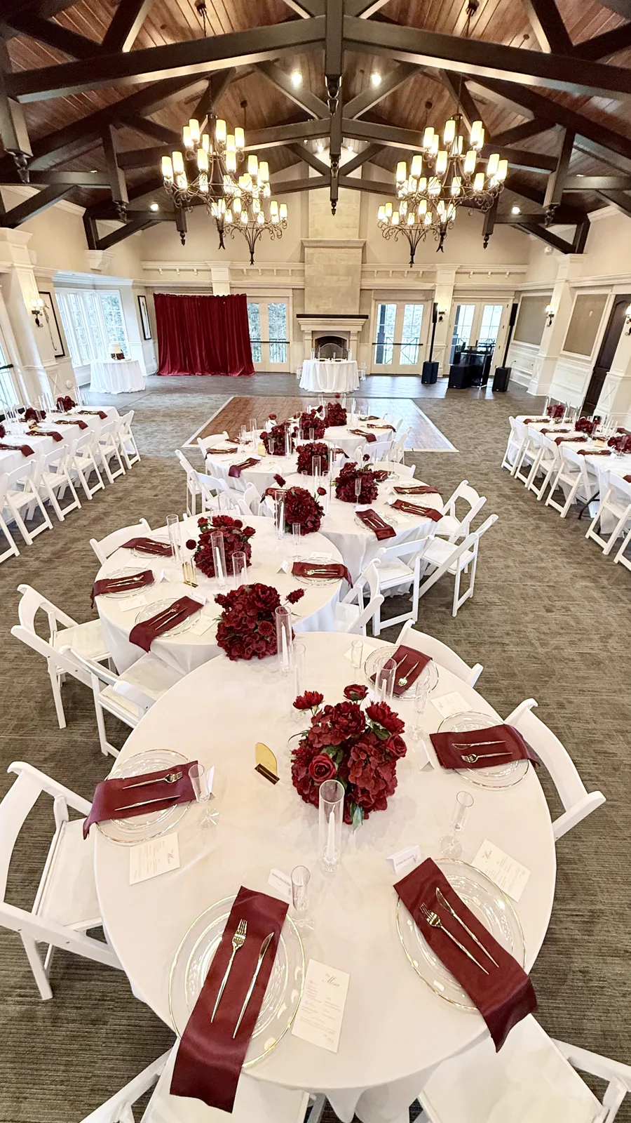 Round tables dressed with red accents in a ballroom