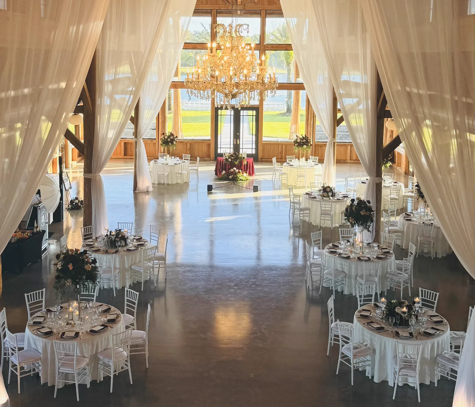 A draped ballroom with chandeliers above round tables