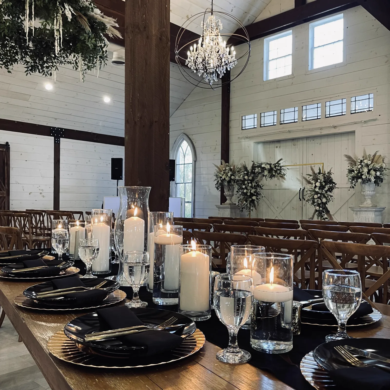 A candlelit banquet table running the length of a barn