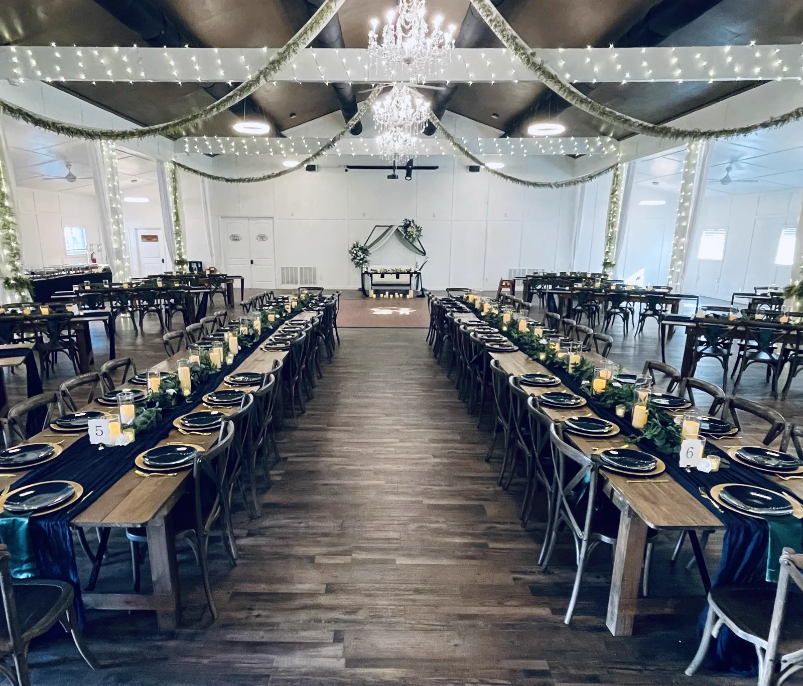 Rows of long tables under string lights in a barn