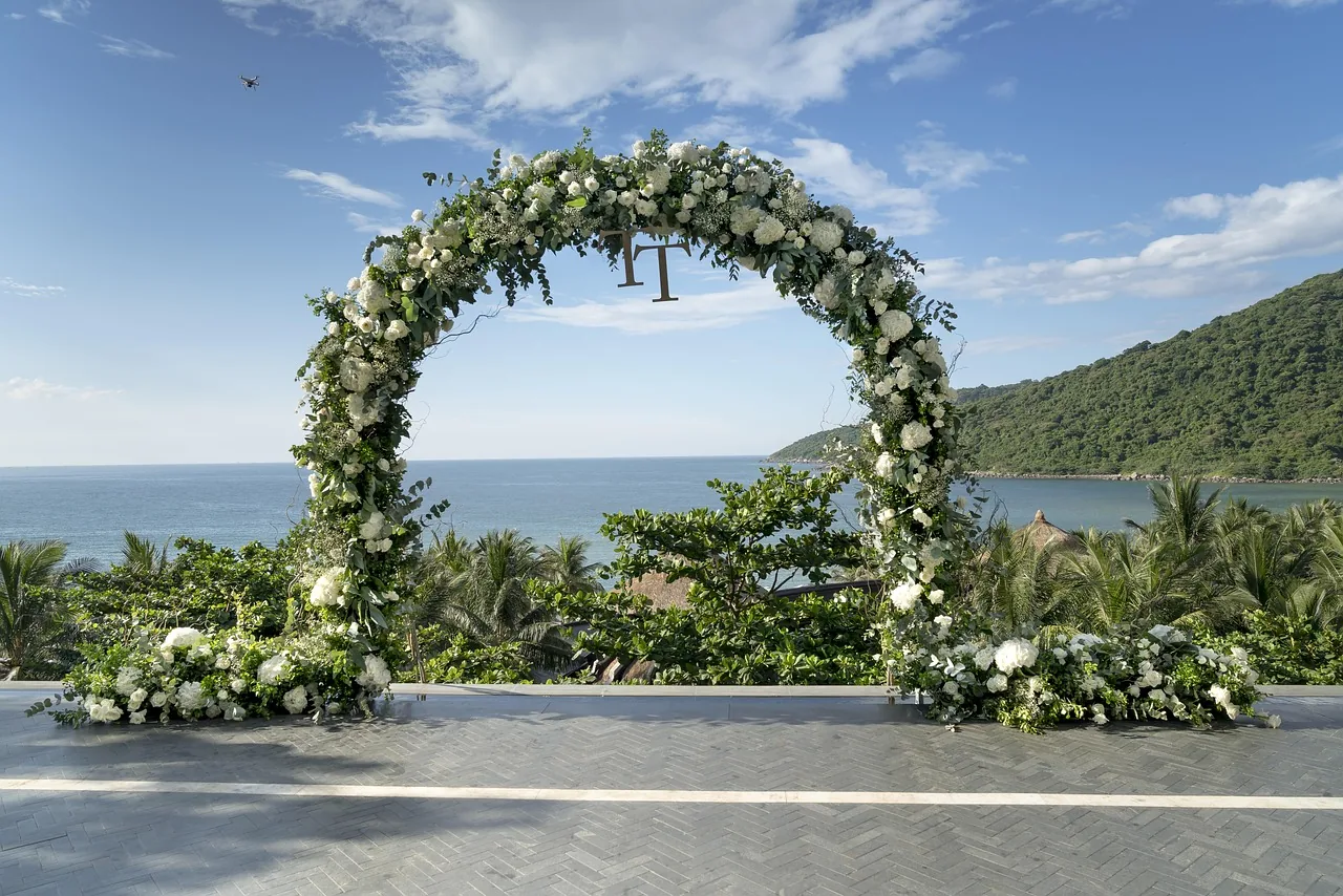 A circular floral ceremony arch overlooking the water.