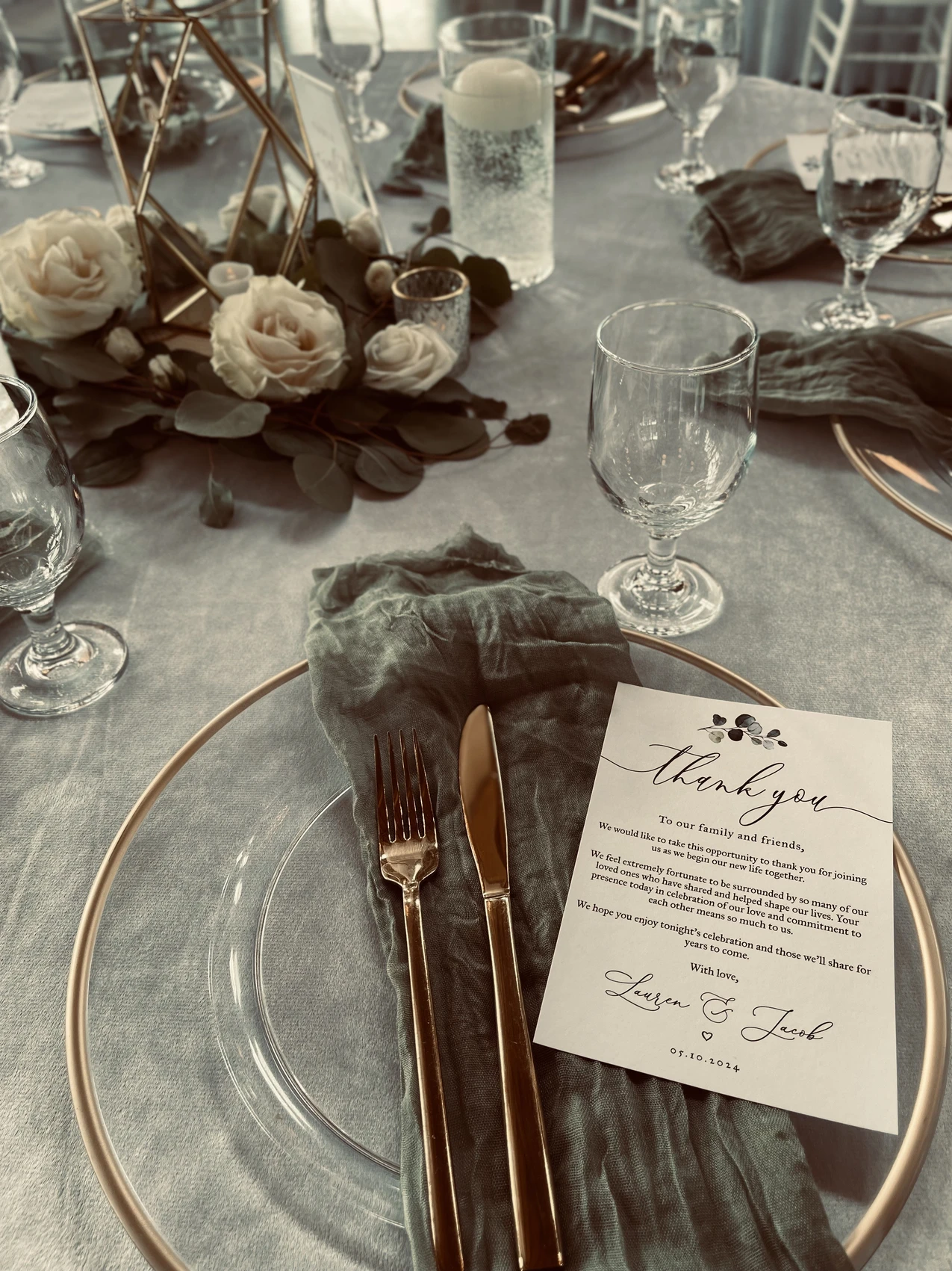 A wedding place setting with layered linens, glassware, and a plated first course.